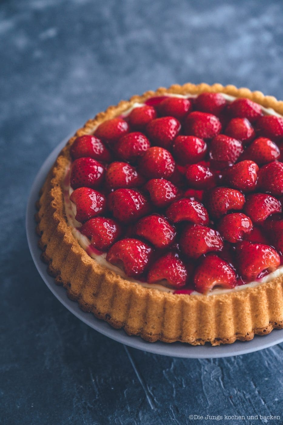 Erdbeerkuchen mit Pudding 3 Erdbeerkuchen mit Pudding 3 | Heute kommen wir wieder mit einem schnellen Klassiker von zu Hause. Eine ganz klassischee Erdbeerkuchen mit Pudding. Ein simpler Obstboden mit etwas Puddingcreme und frischen Erdbeeren drauf. Das ist auch wieder so etwas, dass Oma Lore früher immer schnell mal so aus dem Nichts gezaubert hat. Immer dann, wenn entweder unangekündigter Besuch vor der Türe stand oder sie die Erdbeeren aus dem Garten verarbeiten wollte, damit sie sich nicht zu lange im Kühlschrank stapelten.