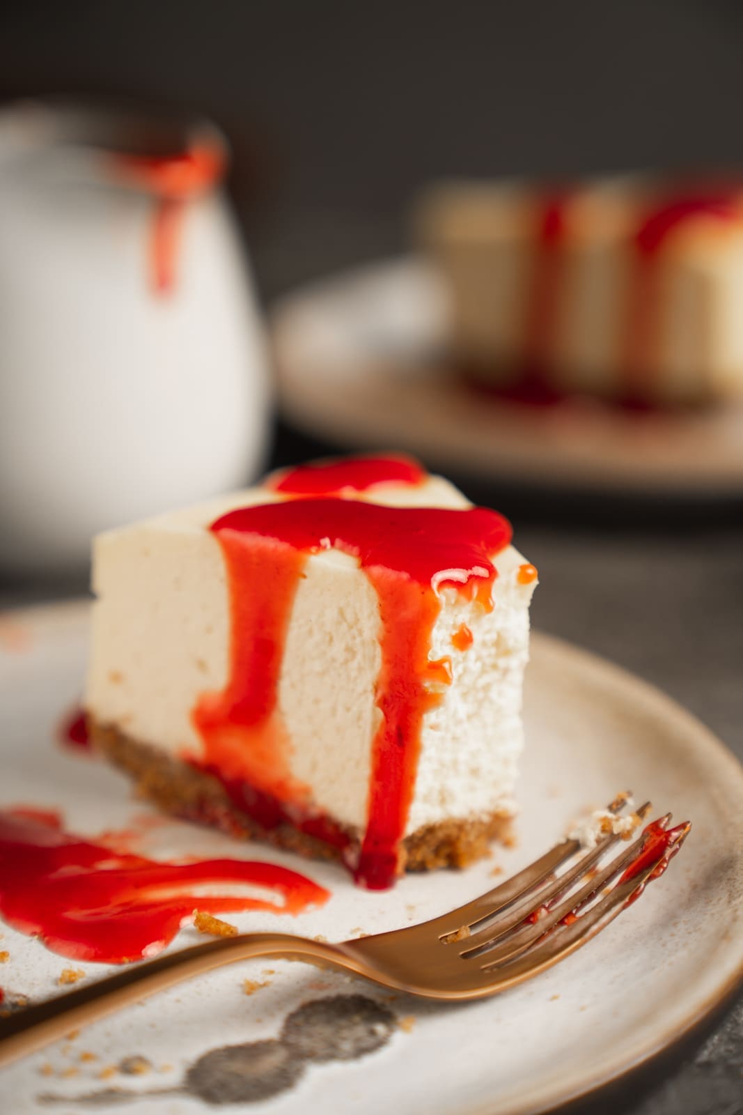 Stück New York Cheesecake mit roter Fruchtsauce auf einem Teller