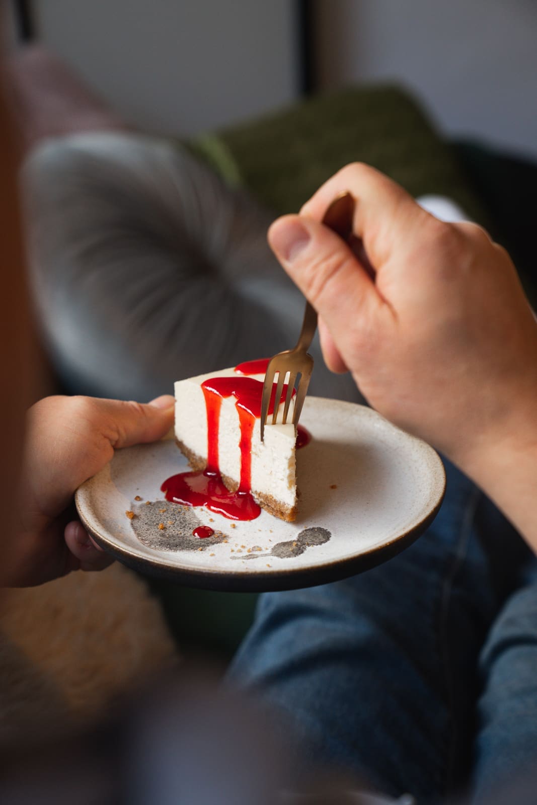 Ein Stück Cheesecake mit Fruchtsauce wird mit der Gabel gegessen