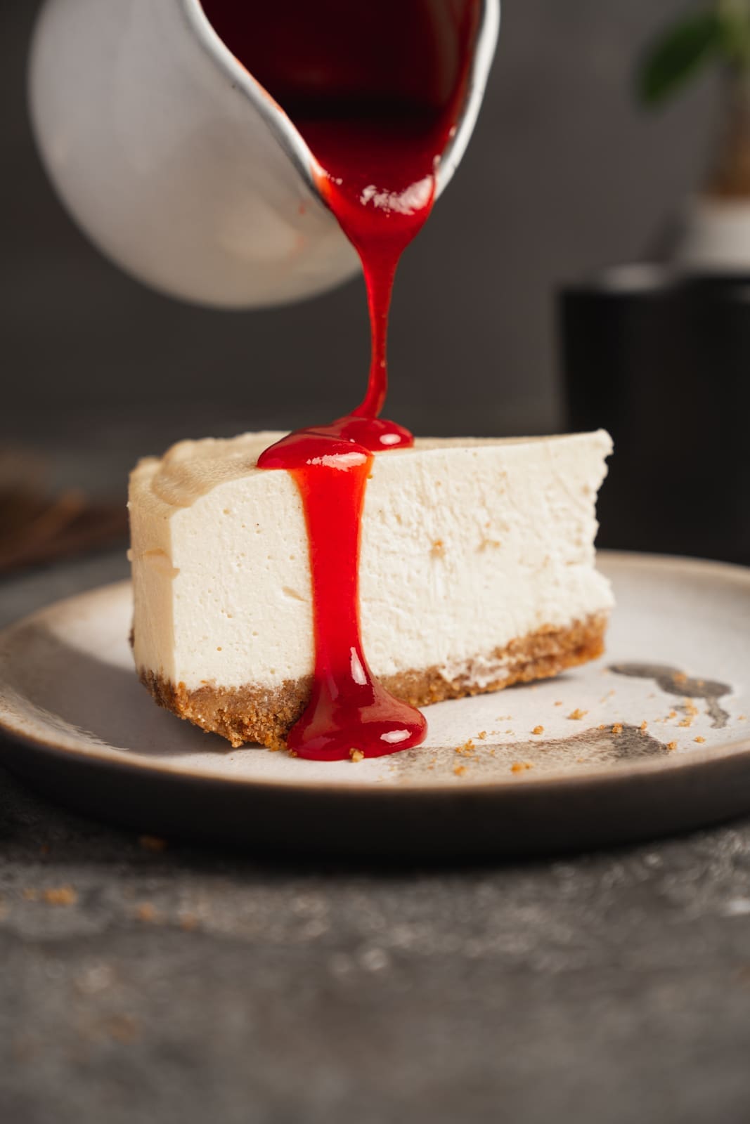 Fruchtsauce wird auf ein Stück American Cheesecake gegossen