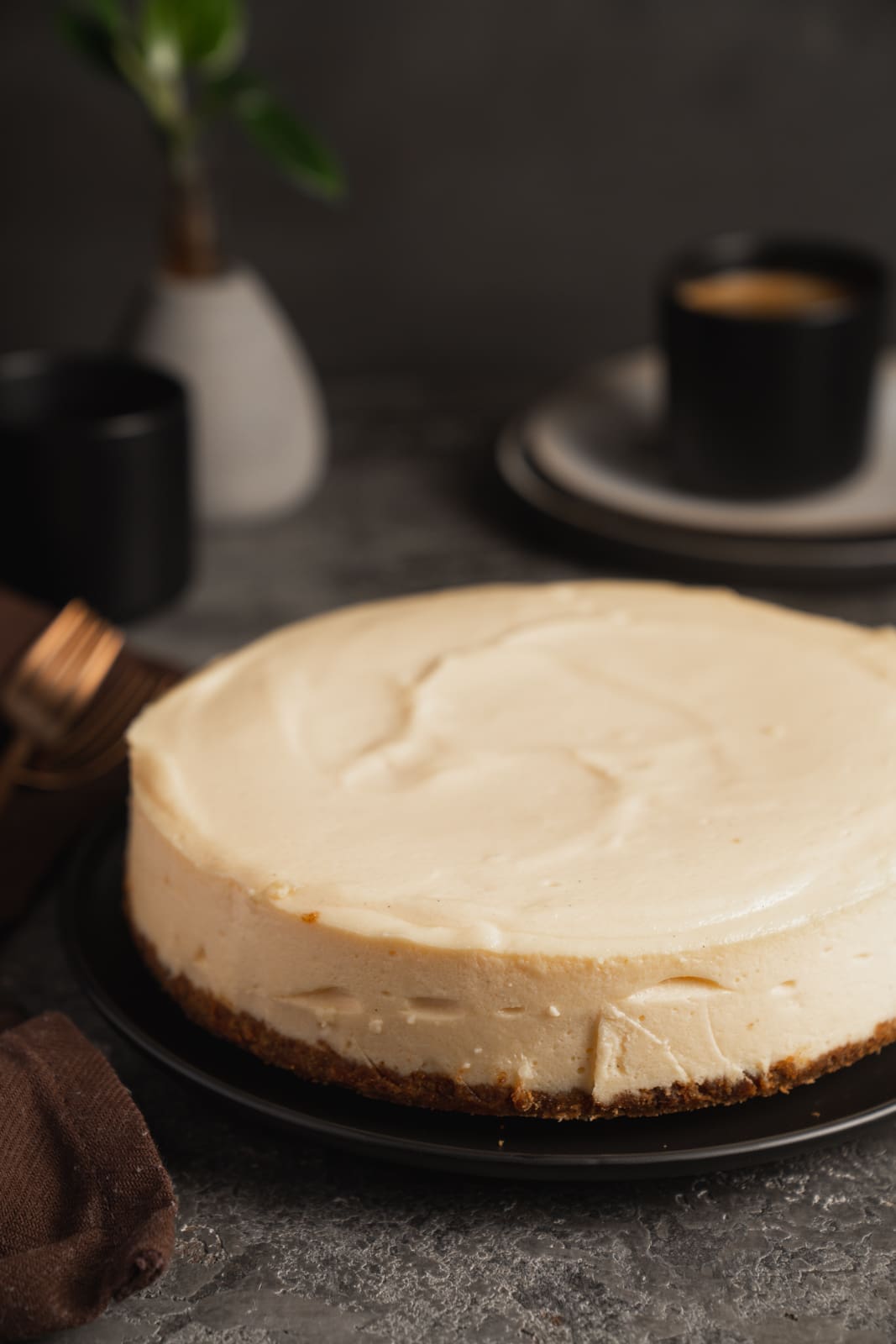 Ganzer New York Cheesecake ohne Risse auf dunkler Tortenplatte