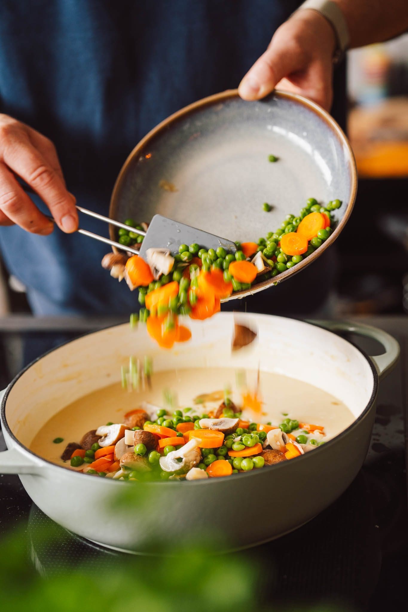 Möhren, Erbsen und Champignons kommen in die helle Frikassee-Sauce