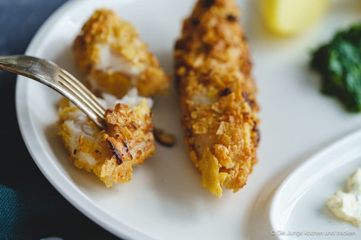 Knusper-Fischstäbchen 5 Fischstäbchen auf Teller / Gabe sticht in Fischstäbchen