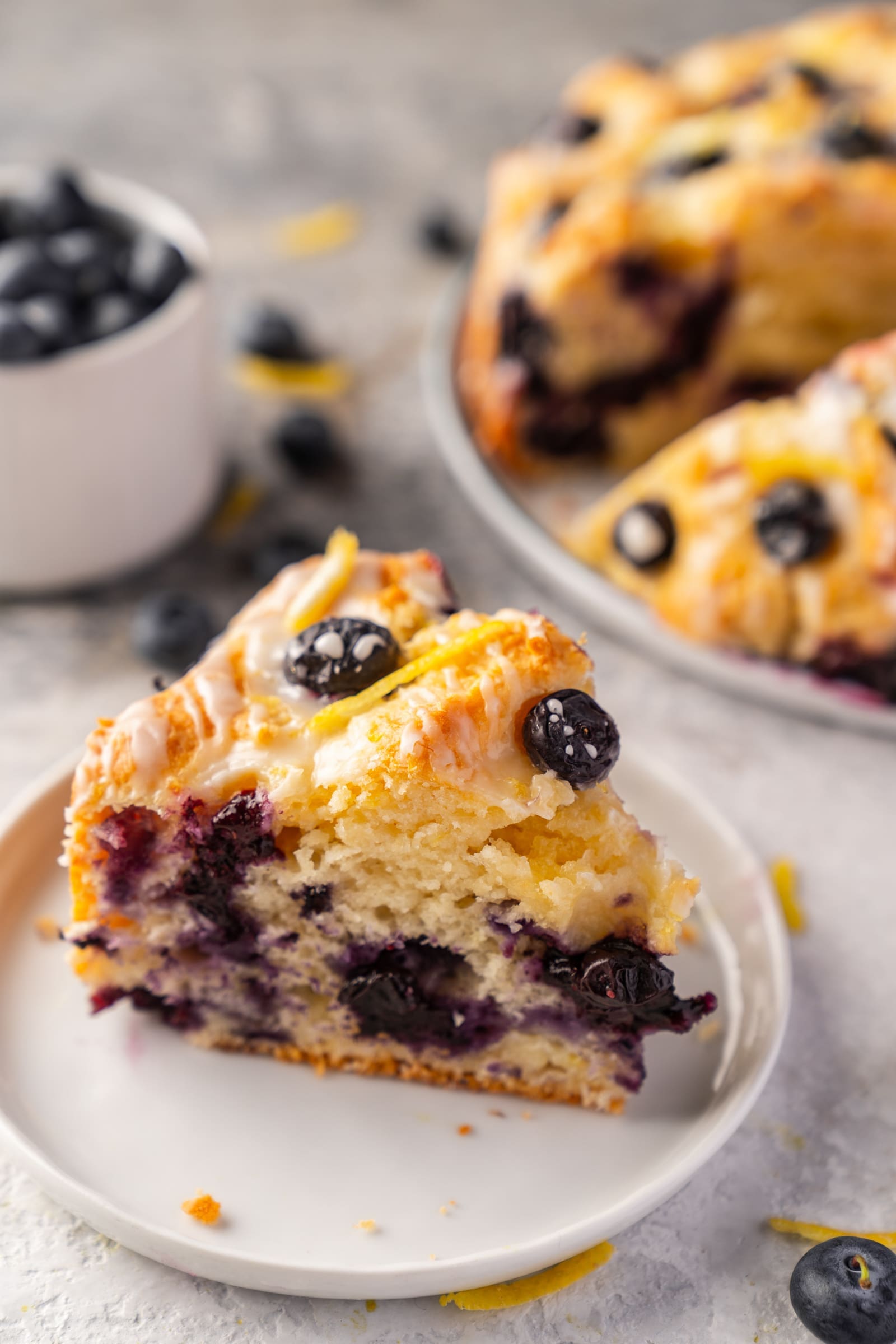 Stück Blaubeerkuchen mit Blaubeeren und Zitronenzesten auf einem Teller