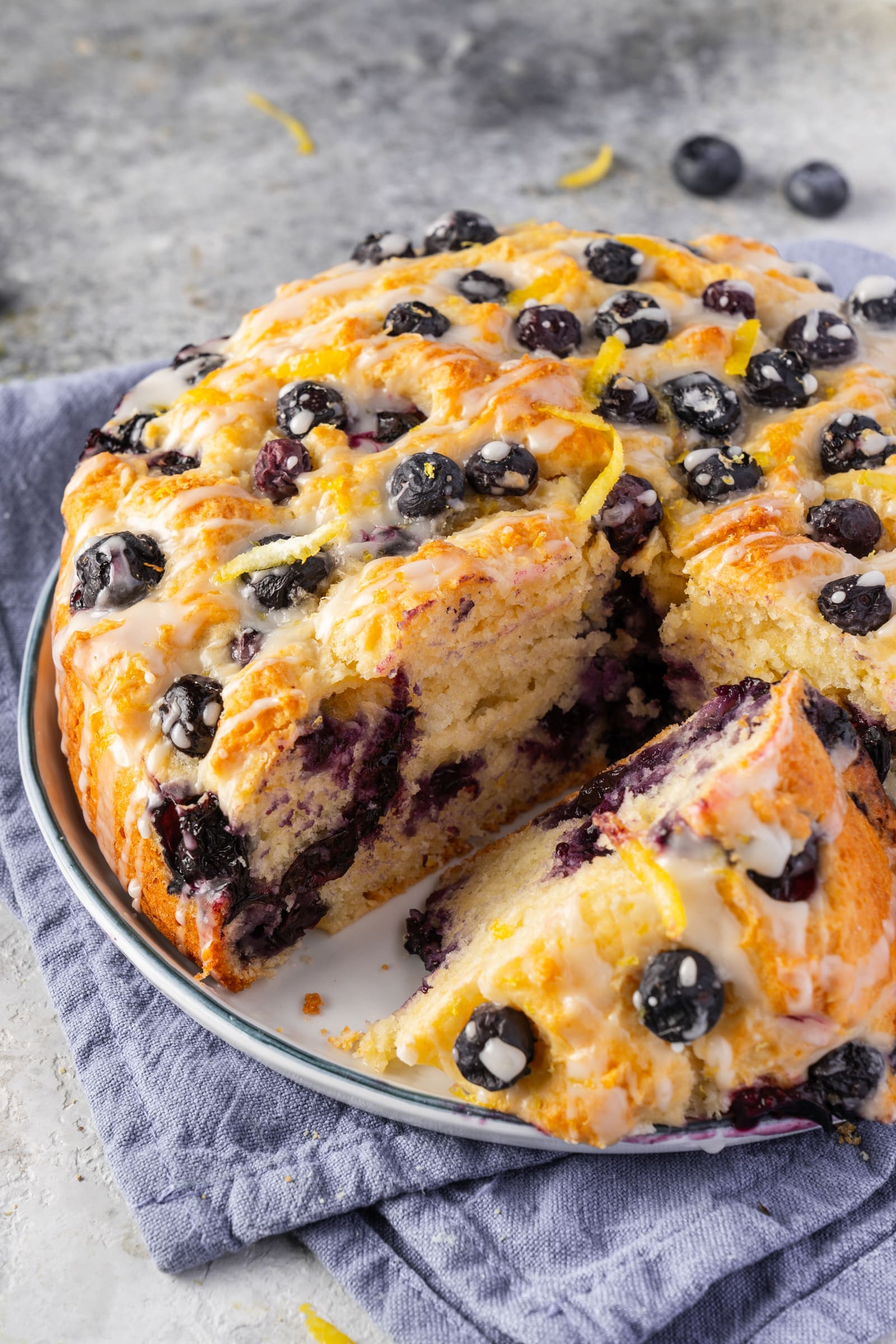 Angeschnittener schneller Blaubeerkuchen mit Zitronenguss und Zesten
