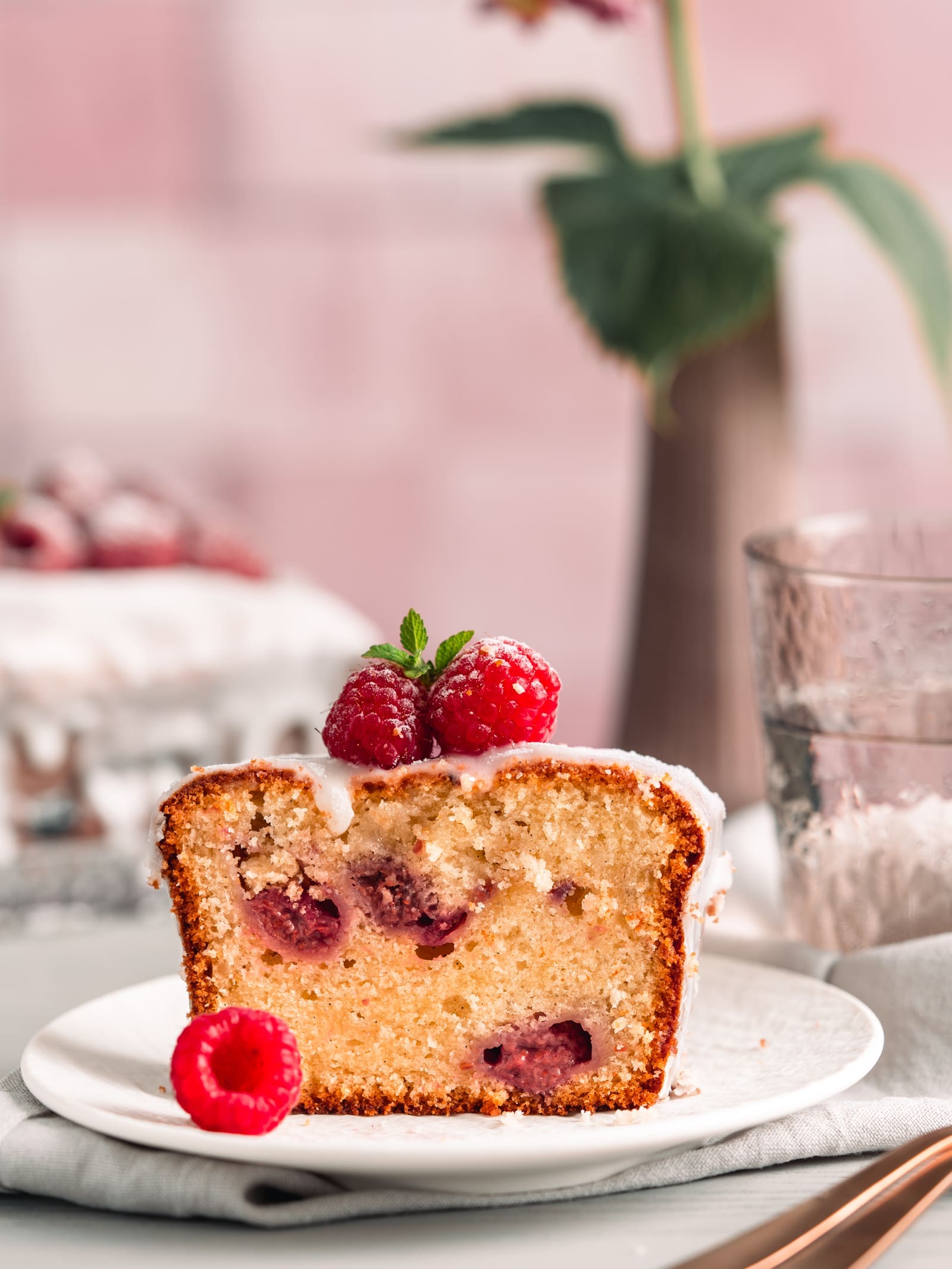 Stück Joghurt-Himbeerkuchen mit Glasur und frischen Himbeeren auf einem Teller